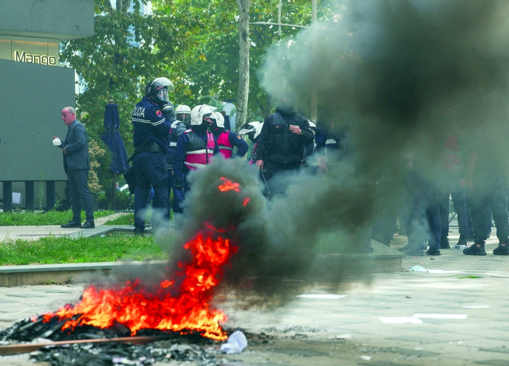 Fire burns as police stand guard during clashes with student protesters in Tirana on Thursday. — Reuters