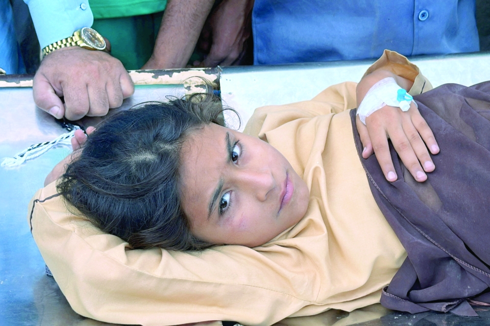 A girl who was injured after a school roof collapse receives first aid at a hospital in Peshawar on Thursday. — Reuters 