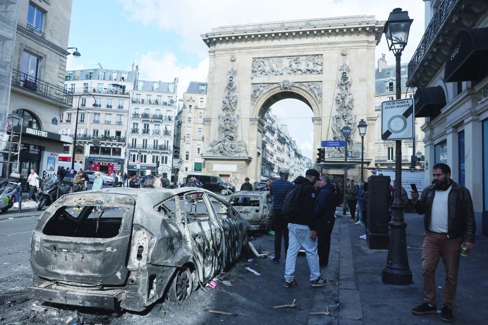 People inspect a destroyed vehicle, the day after clashes during a national day of demonstrations against the cost of living and rising fuel prices, in Paris, France, October 18, 2026. REUTERS
