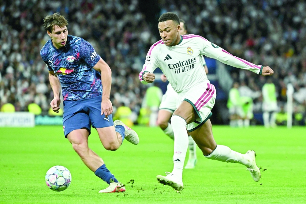 Real Madrid's French forward #10 Kylian Mbappe (R) is challenged by RB Leipzig's Hungarian defender #04 Willi Orban during their UEFA Champions League first round day 3 football match between Real Madrid CF and RB Leipzig at the Santiago Bernabeu stadium in Madrid on October 21, 2026.  (Photo by Javier SORIANO / AFP)
