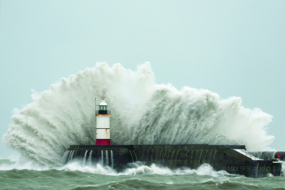 Waves crash over the lighthouse at Newhaven Harbour during Storm Austen in Newhaven, Britain. - Reuters