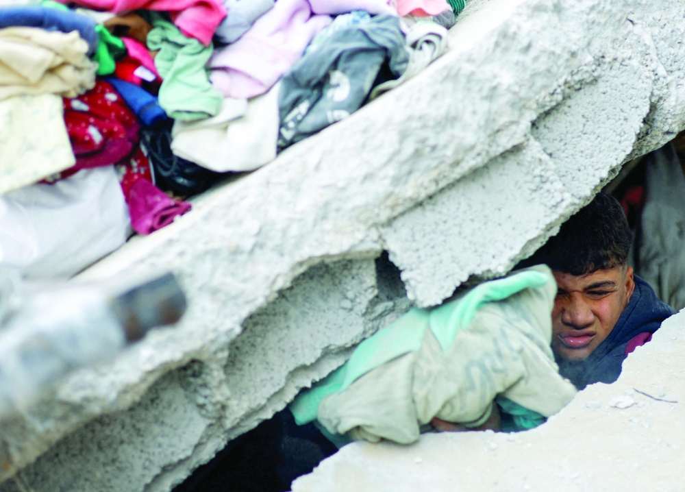 A Palestinian looks through the rubble as people clear the debris at the site of a house targeted by an Israeli air strike after the Israeli military warned the residents of the house to evacuate on Thursday, in Nuseirat in the central Gaza Strip. 