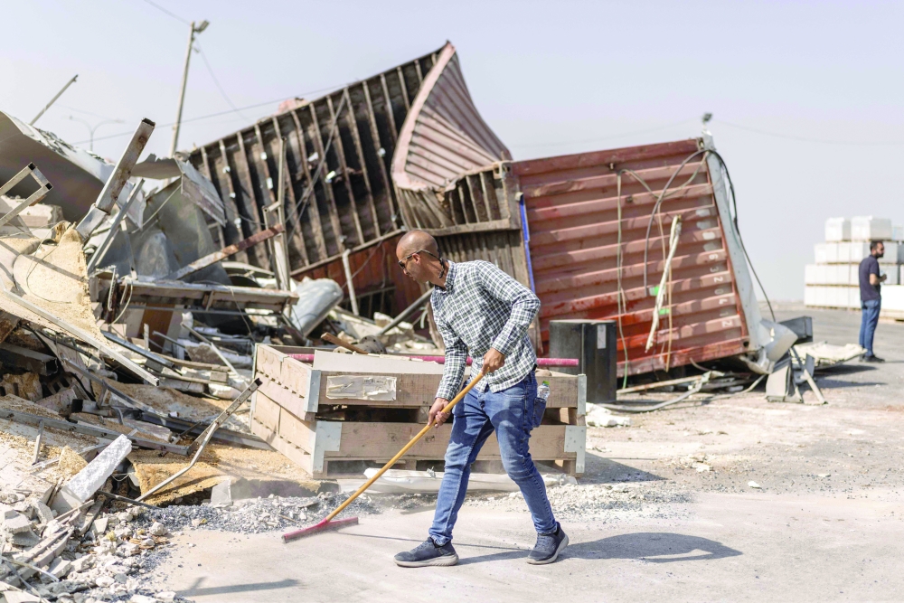 A Palestinian man clears debris outside a business that was demolished by the Israeli army in the West Bank. — AFP
