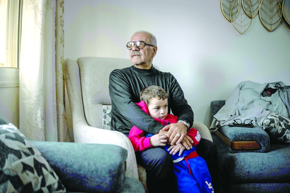 Khaled Shawer al Tamimi, who was evicted alongside his family from Ein Deir Baha neighbourhood by Israeli forces, poses for a picture with his grandson in Hebron, in the occupied West Bank, on Saturday. — AFP