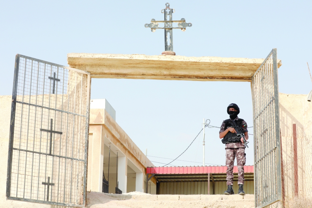 A member of the security forces stands guard during preparations for the funeral of victims of a church shooting in Karak. — Reuters