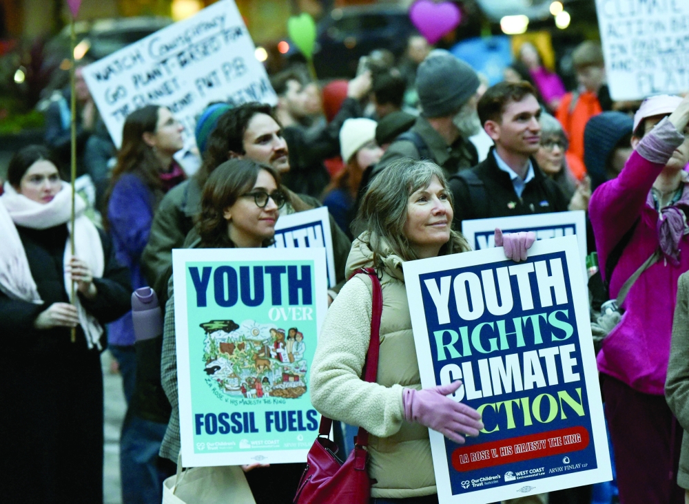Supporters of the first federal youth climate trial hold up signs during a rally in Vancouver, Canada. — AFP