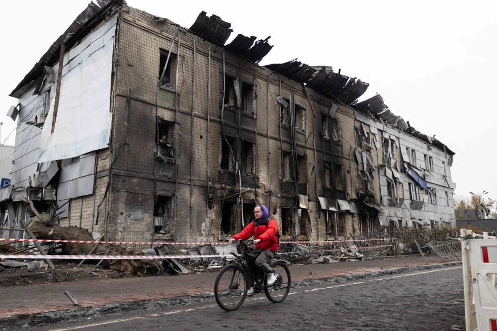 A man rides a bicycle past a building damaged following an air attack in Kyiv. — AFP 