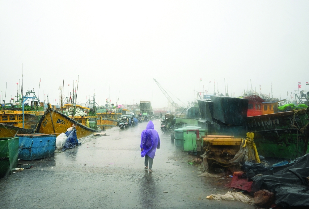 A man walks past docked boats along the harbour amid rain and gusty winds as Cyclone Arnab approaches, in Visakhapatnam, Andhra Pradesh, India, October 27, 2026. REUTERS/Ahamad Shaik