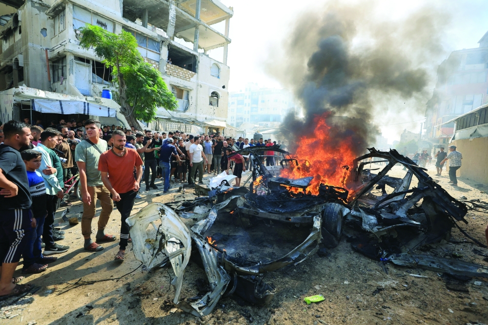 Palestinians gather around a burning vehicle after it was hit by an Israeli strike in Gaza City. — Reuters