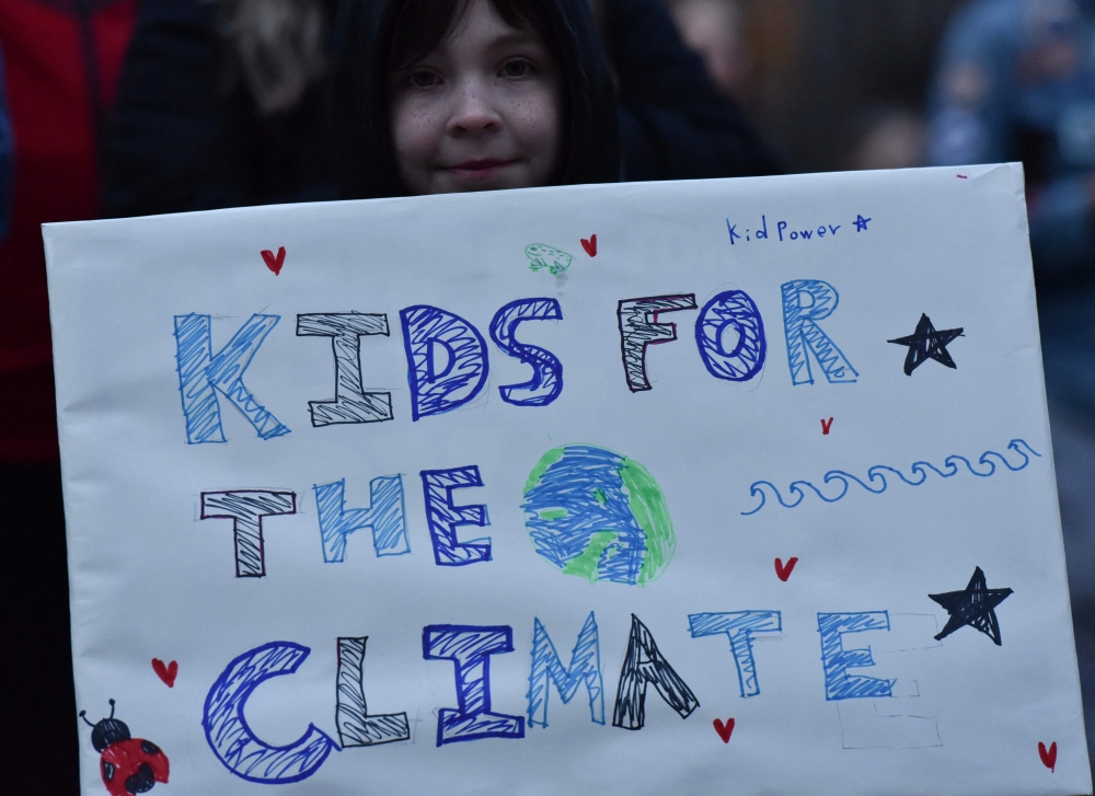 Supporters of the first federal youth climate trial in Canadian history hold up signs during a rally outside the Vancouver Art Gallery in Vancouver, British Colombia, Canada on October 26, 2026. 