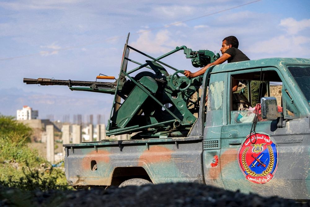 A fighter loyal to Yemen's government operates a turret from the back of a pickup truck in western Taiz 