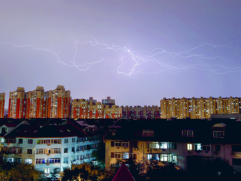 Lightning strikes across the sky above residential buildings during a thunderstorm in Beijing
