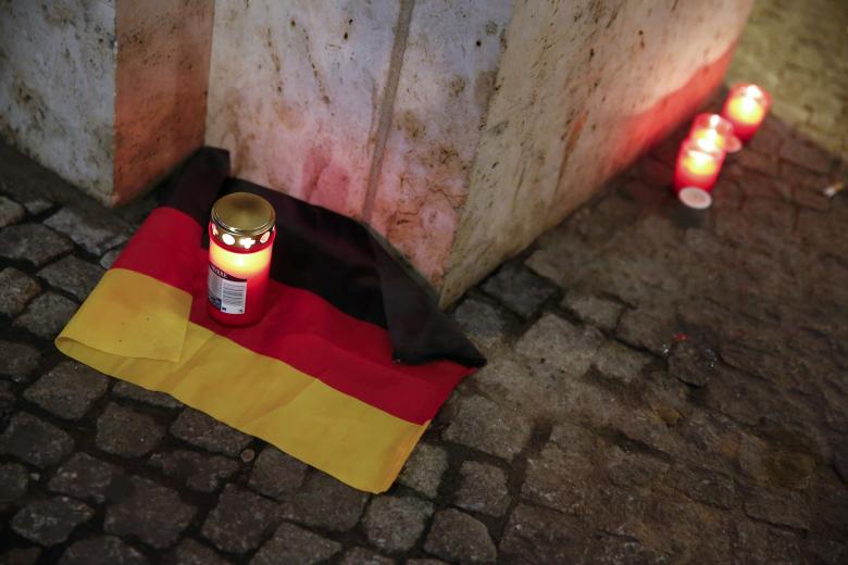 A candle is burning on a German national flag near the site where a truck ploughed through a crowd at a Berlin Christmas market
