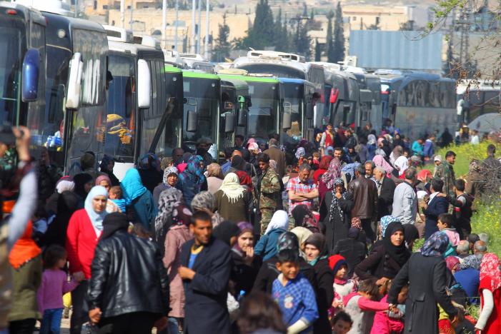 People that were evacuated from the two villages of Kefraya and al-Foua walk near buses, after a stall in an agreement between rebels and Syria's army, at insurgent-held al-Rashideen, Aleppo province