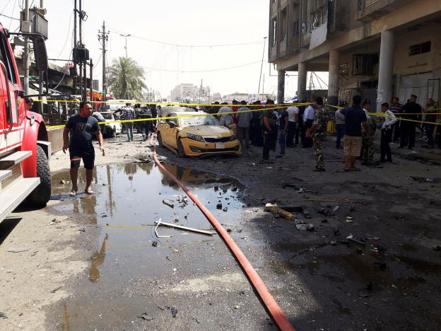 Iraqi people gather at the site of car bomb attack near a government office in Karkh district in Baghdad