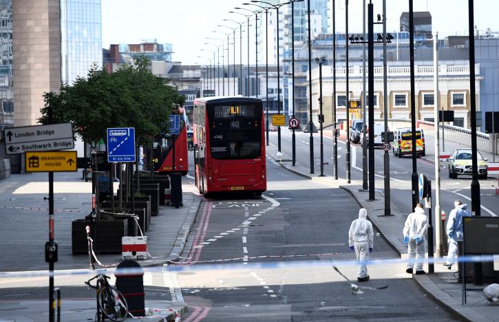 Police forensics investigators work on London Bridge near abandoned buses after an attack left 6 people dead and dozens injured in London