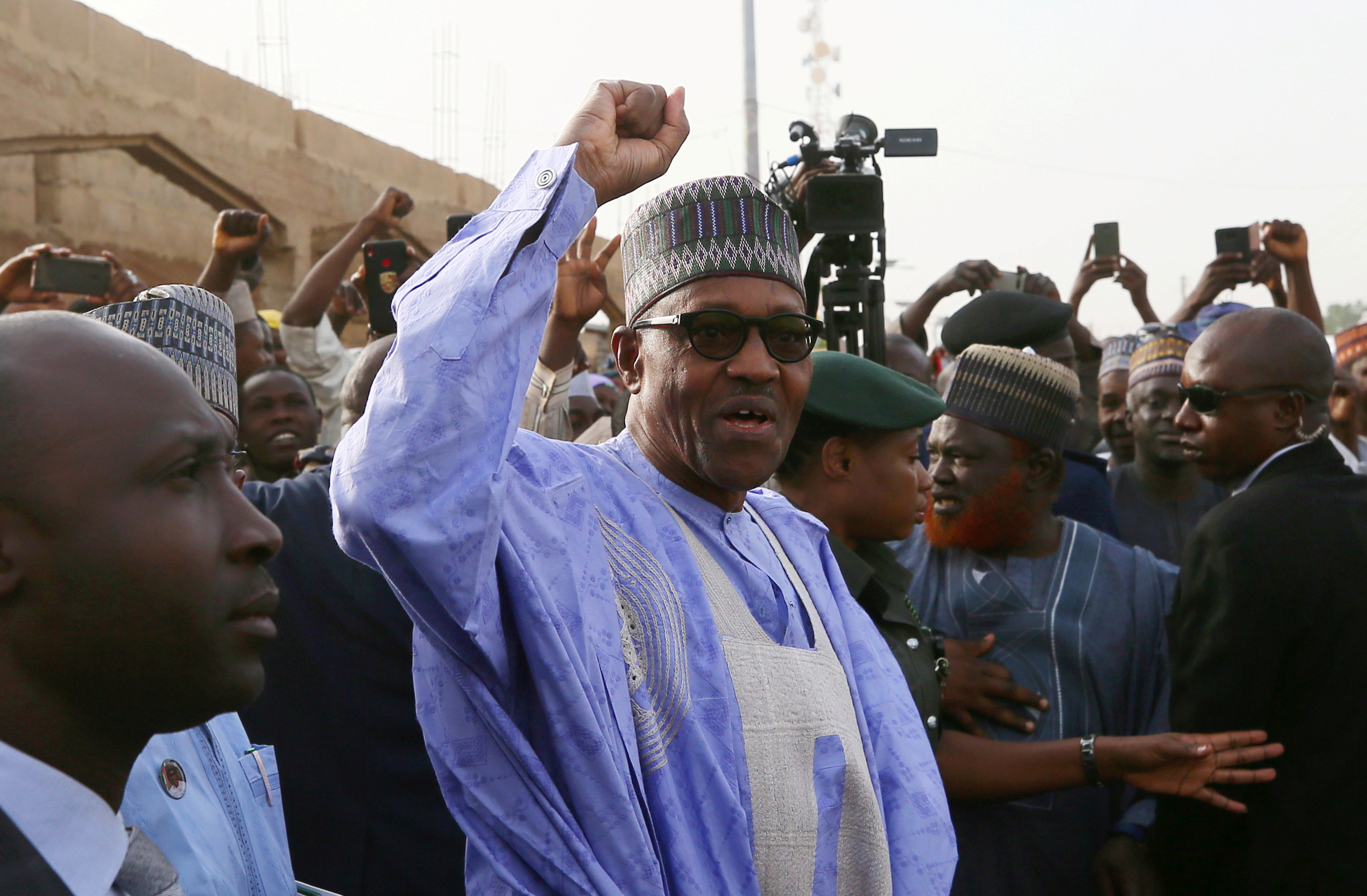 FILE PHOTO: Nigerian President Muhammadu Buhari gestures as he arrives to cast a vote in Nigeria's presidential election at a polling station in Daura