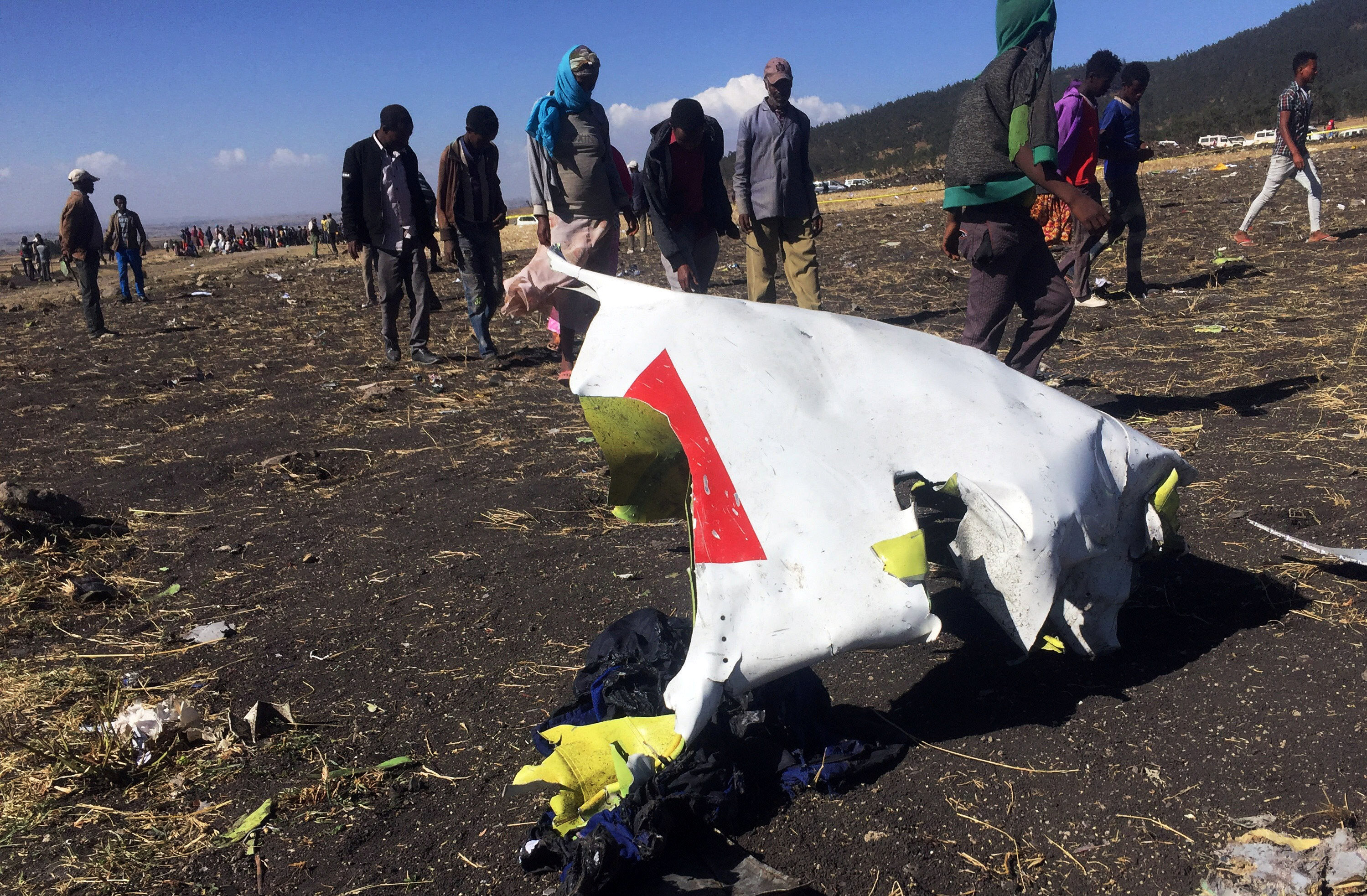 People walk past a part of the wreckage at the scene of the Ethiopian Airlines Flight ET 302 plane crash, near the town of Bishoftu, southeast of Addis Ababa