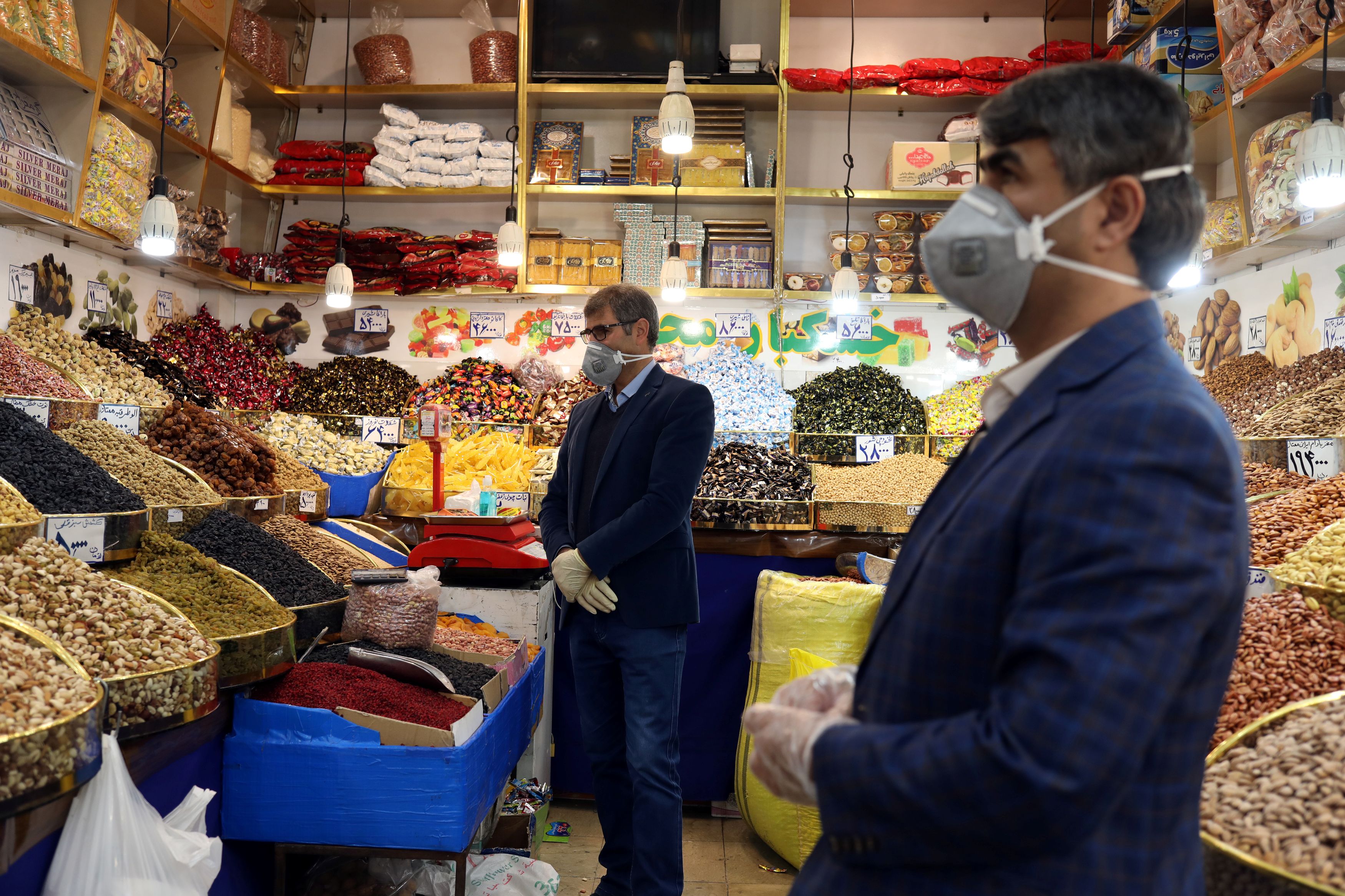 Men wear protective face masks and gloves, following the outbreak of coronavirus, as they are seen in a nuts shop in Tehran