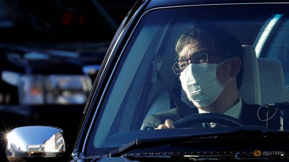 a-taxi-driver-wearing-a-surgical-mask-sits-inside-a-taxi-in-front-of-yokohama-station-in-yokohama-1