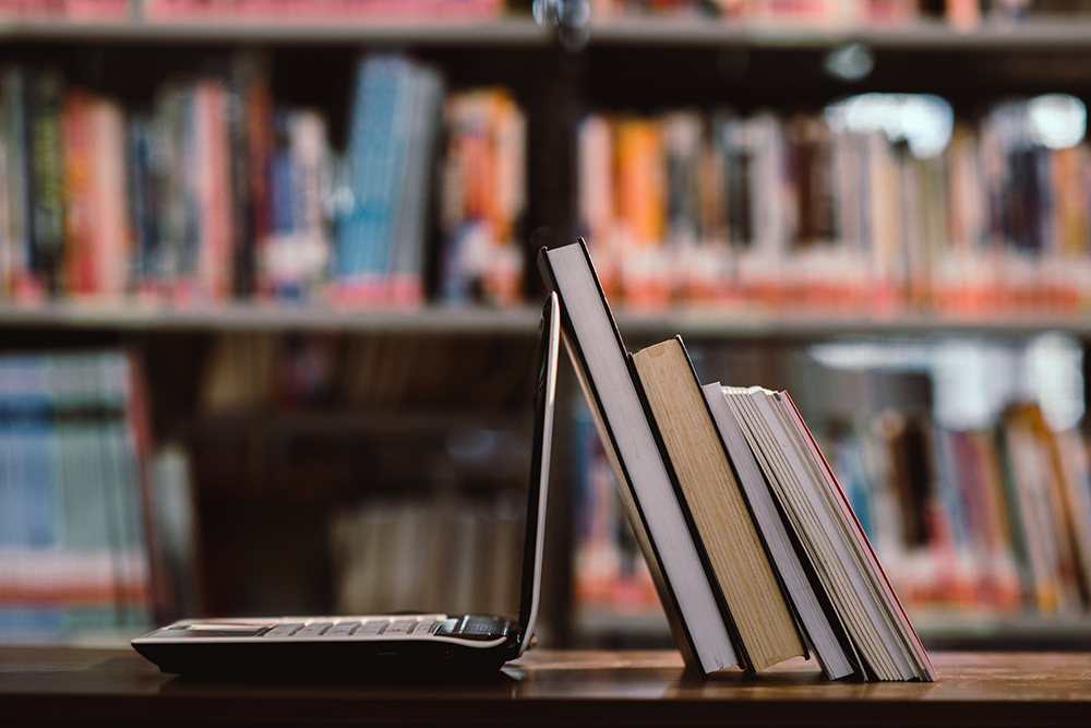 laptop computer and book on workplace in library room,Education